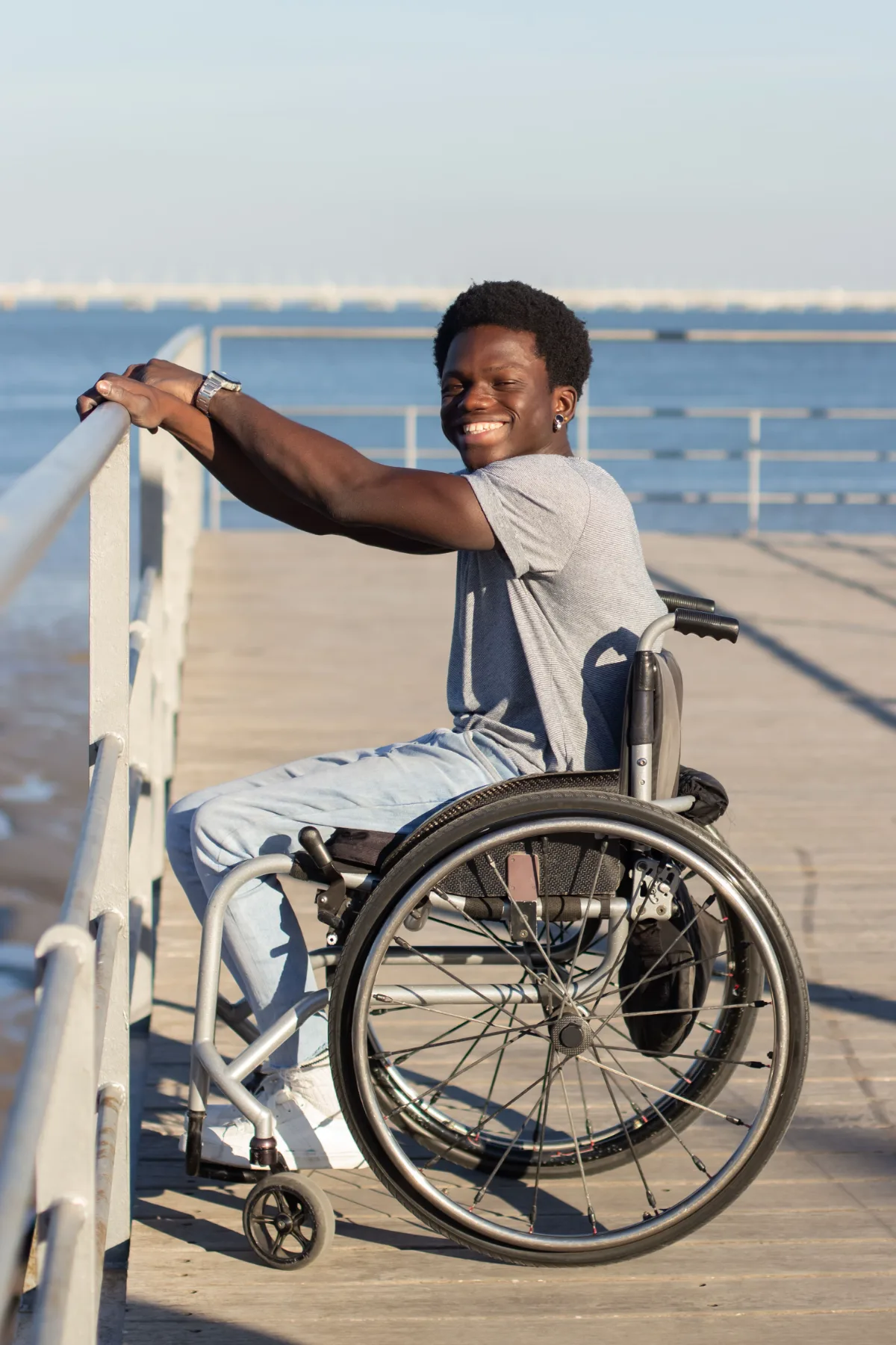 A man in a wheelchair resting beside the water on a boardwalk