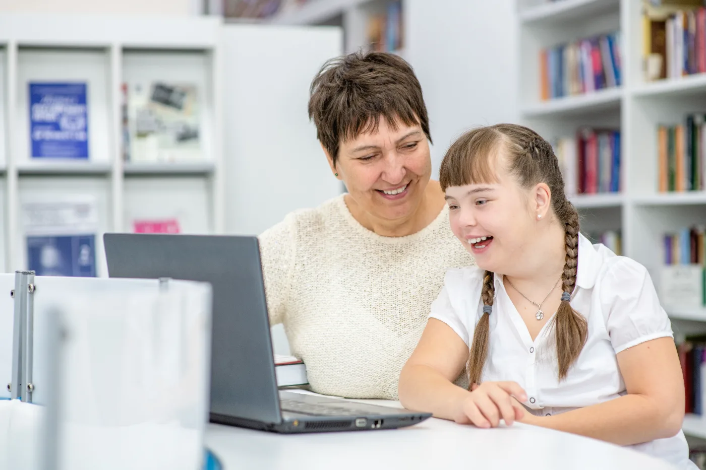 A support coordinator and a participant reading an NDIS plan together at a laptop