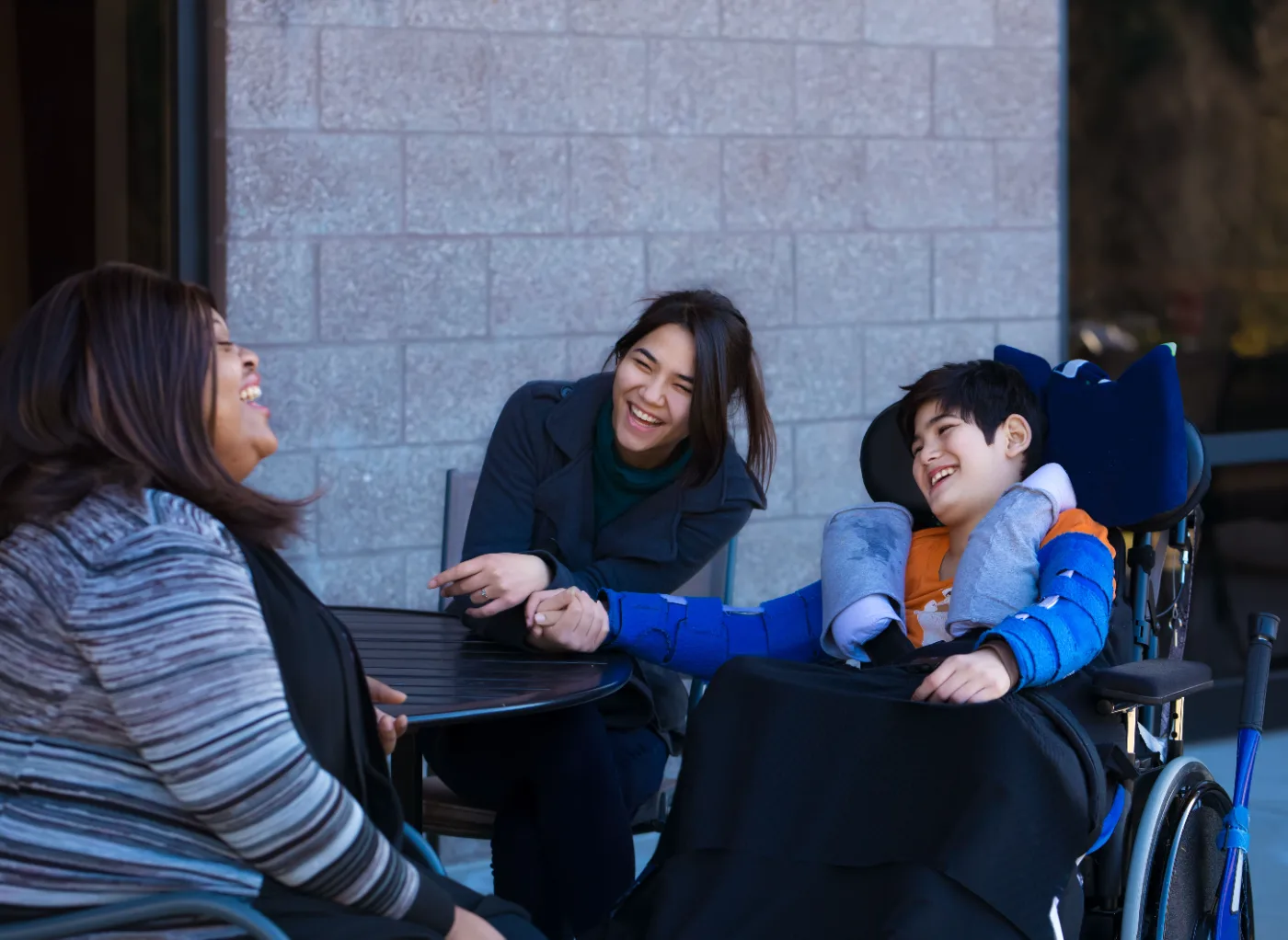 A participant and two supporters talking and laughing around an outdoor table