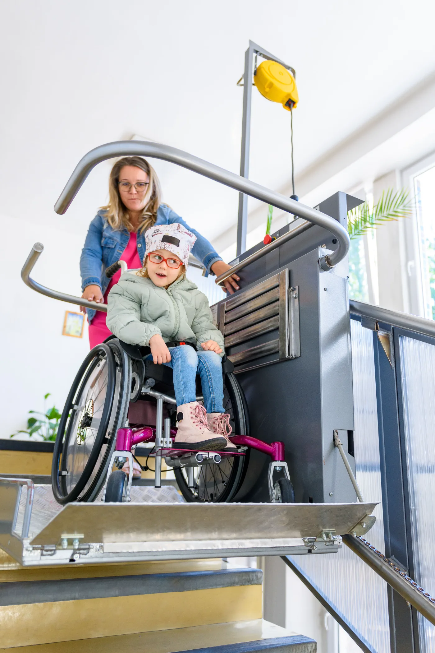 A child in a wheelchair using an accessible platform lift with a support worker